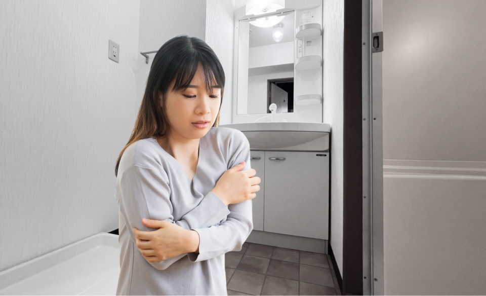 脱衣所で寒さで震える女性